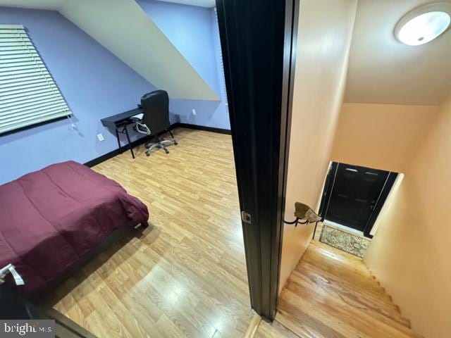 bedroom with light wood-type flooring and vaulted ceiling