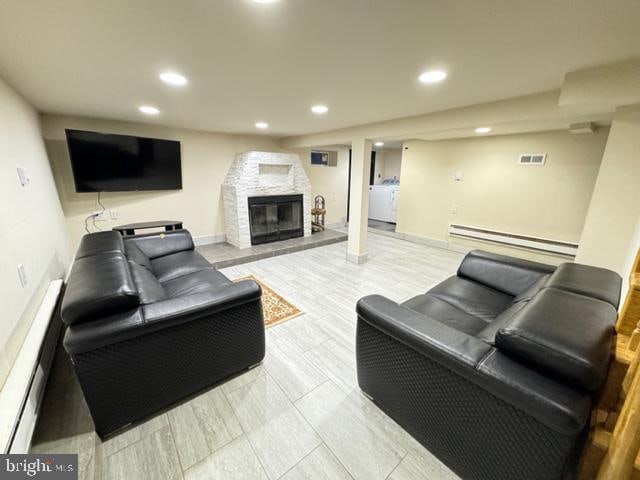 living room with a stone fireplace and baseboard heating