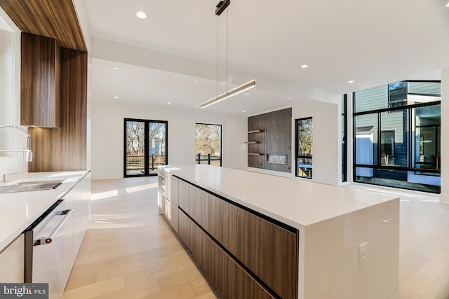 kitchen featuring a spacious island, sink, dishwashing machine, light hardwood / wood-style floors, and white cabinets