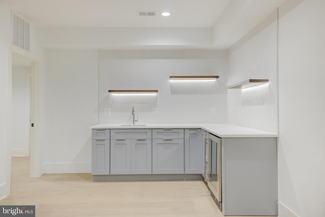 kitchen with sink, gray cabinetry, backsplash, and light wood-type flooring