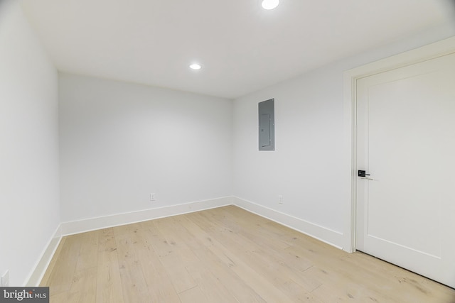 spare room featuring electric panel and light hardwood / wood-style floors