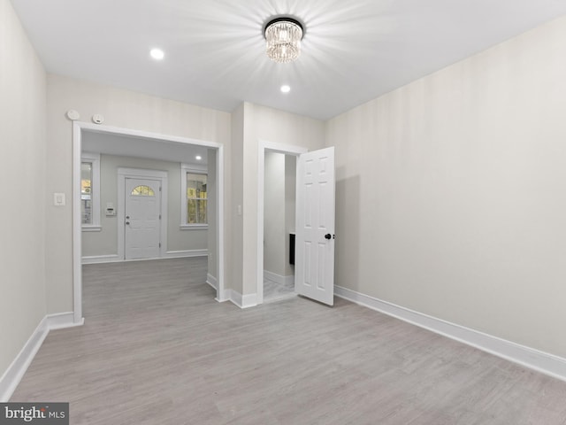 empty room featuring light hardwood / wood-style floors and a notable chandelier