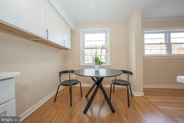 dining space with light wood-type flooring and crown molding