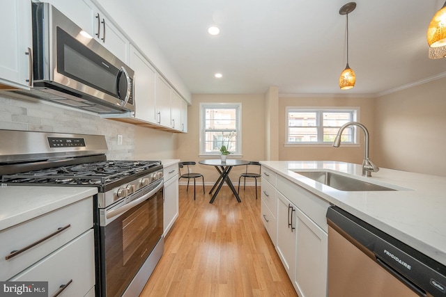 kitchen featuring white cabinets, decorative light fixtures, stainless steel appliances, and a wealth of natural light