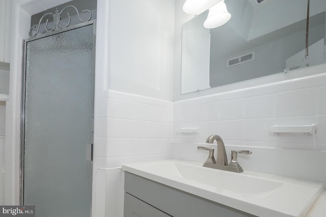 bathroom with decorative backsplash, vanity, and a shower with door