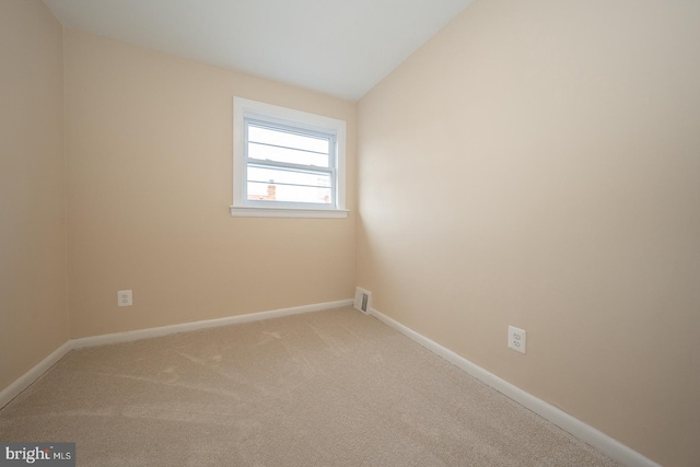 carpeted empty room featuring lofted ceiling