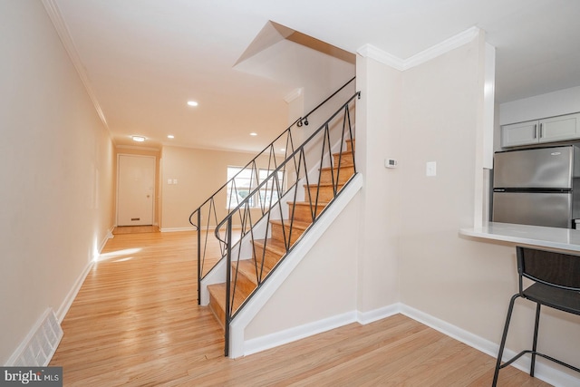 stairs featuring wood-type flooring and ornamental molding