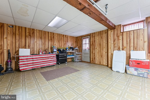 misc room with a paneled ceiling and wood walls