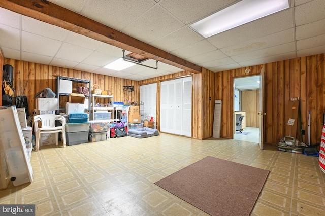 basement with a paneled ceiling and wood walls