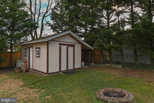 view of outbuilding with a lawn and an outdoor fire pit