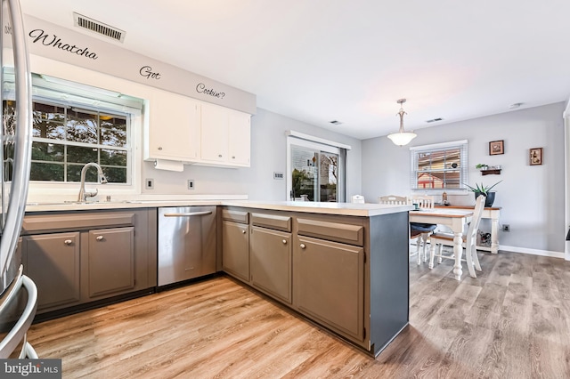 kitchen with kitchen peninsula, light wood-type flooring, stainless steel appliances, decorative light fixtures, and white cabinetry