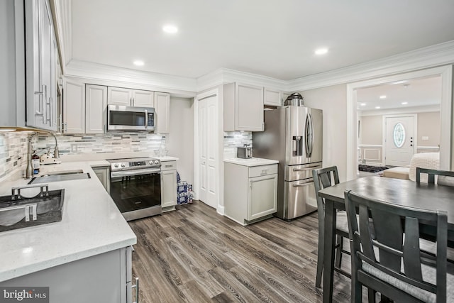 kitchen featuring appliances with stainless steel finishes, crown molding, dark wood-type flooring, sink, and gray cabinets