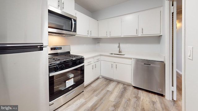 kitchen featuring white cabinets, stainless steel appliances, light hardwood / wood-style flooring, and sink