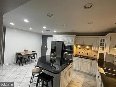 kitchen with a center island, light tile patterned floors, stainless steel appliances, and tasteful backsplash