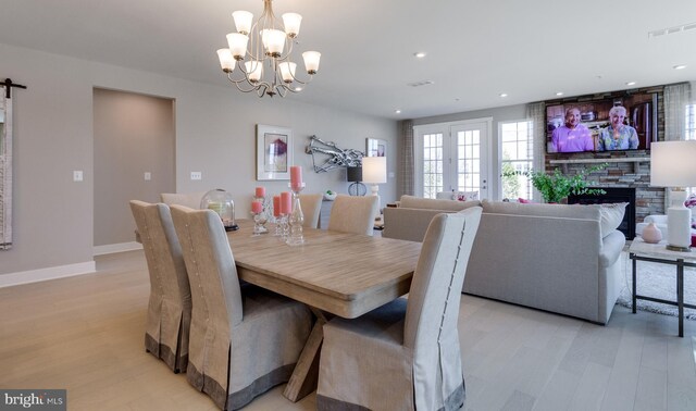 dining area with an inviting chandelier, a barn door, a fireplace, and light hardwood / wood-style flooring