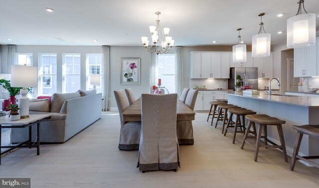 dining space with plenty of natural light, sink, a chandelier, and light hardwood / wood-style flooring