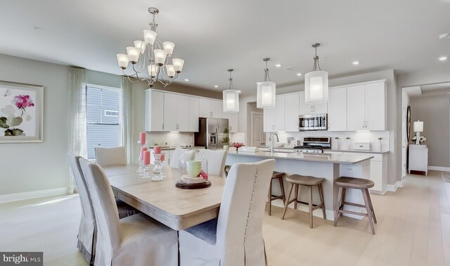 dining room featuring light wood-type flooring, sink, and an inviting chandelier