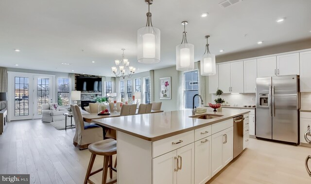 kitchen with white cabinetry, sink, an island with sink, pendant lighting, and appliances with stainless steel finishes