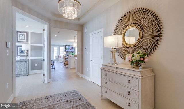 hallway with a chandelier and light wood-type flooring