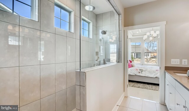 bathroom with tile patterned floors, plenty of natural light, a chandelier, and tiled shower