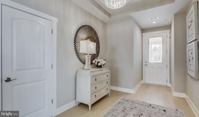 foyer featuring light wood-type flooring and a notable chandelier