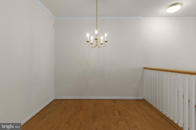 spare room with hardwood / wood-style floors, crown molding, and a chandelier