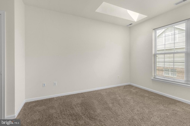 carpeted empty room featuring a skylight