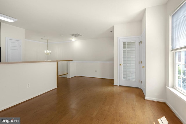 spare room with hardwood / wood-style flooring and a notable chandelier