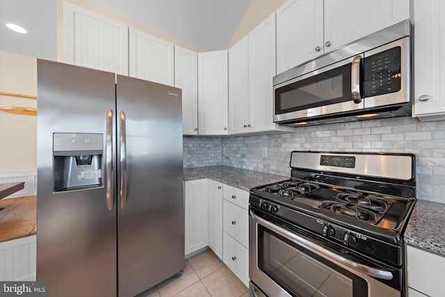 kitchen featuring white cabinets, stainless steel appliances, and dark stone counters