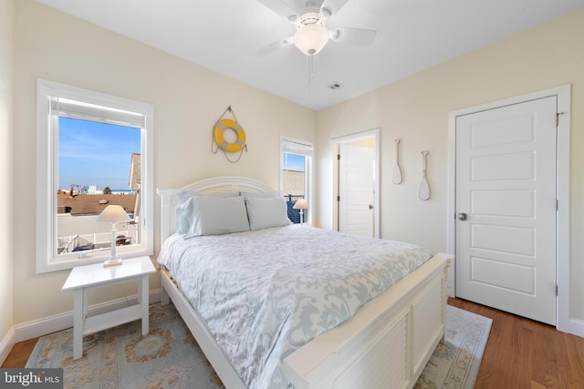 bedroom featuring ceiling fan, wood-type flooring, and multiple windows