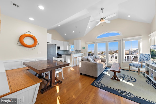 living room featuring light wood-type flooring, high vaulted ceiling, and ceiling fan