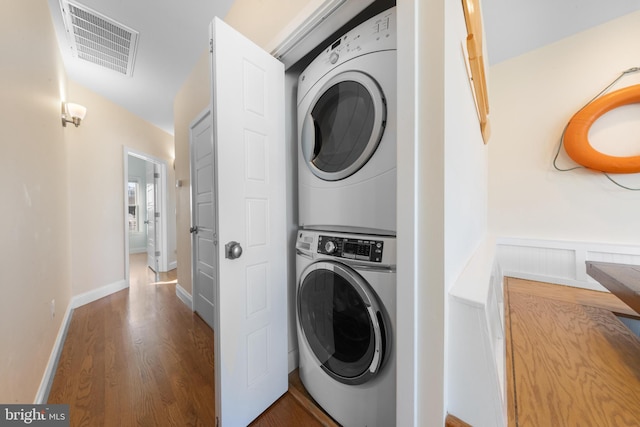 laundry area featuring stacked washing maching and dryer and wood-type flooring