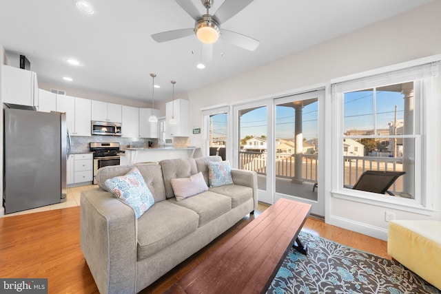 living room with ceiling fan and light hardwood / wood-style flooring