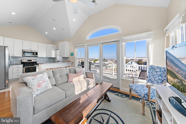 living room featuring high vaulted ceiling, light hardwood / wood-style flooring, ceiling fan, and sink