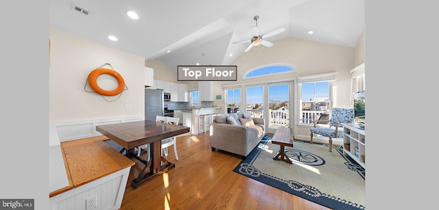 living room with ceiling fan, high vaulted ceiling, and light hardwood / wood-style flooring