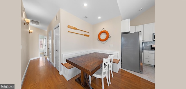 dining space featuring light wood-type flooring and vaulted ceiling