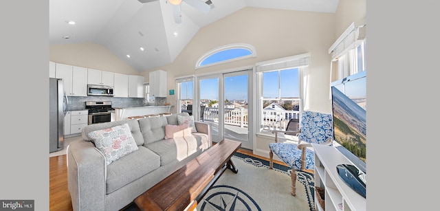 living room featuring light hardwood / wood-style floors, high vaulted ceiling, and ceiling fan