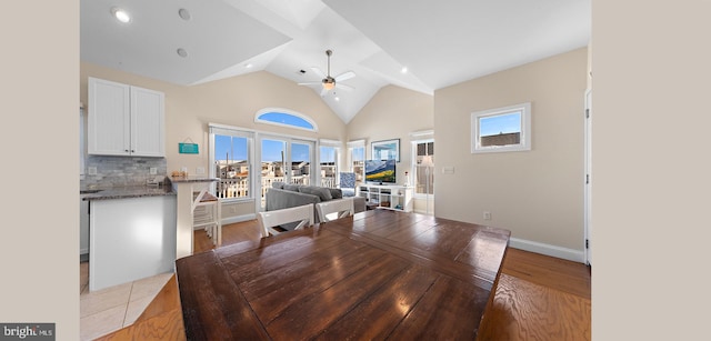 dining area with ceiling fan, a healthy amount of sunlight, light hardwood / wood-style floors, and high vaulted ceiling