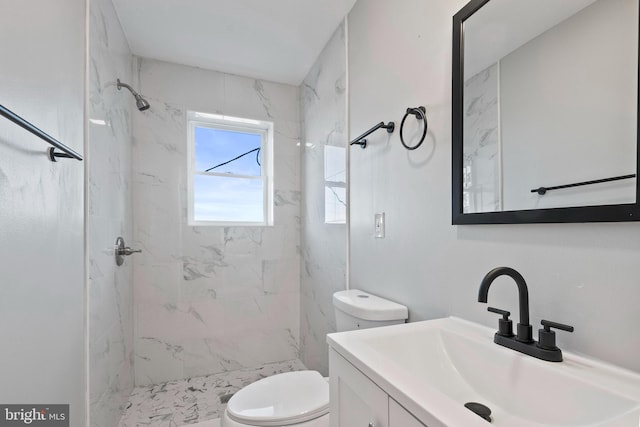 bathroom featuring vanity, toilet, and a tile shower