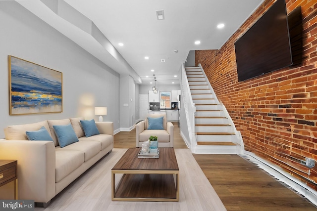 living room featuring brick wall and light hardwood / wood-style flooring