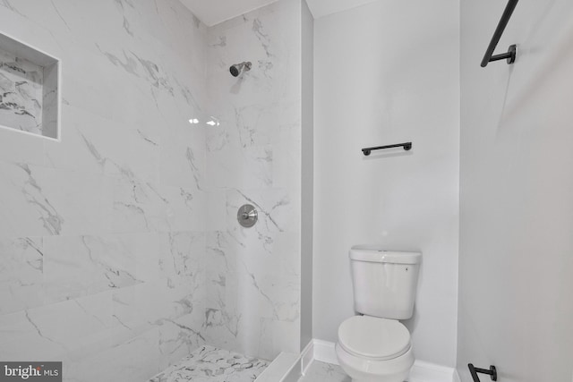 bathroom featuring a tile shower and toilet