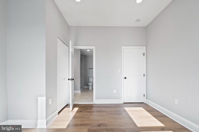 unfurnished bedroom featuring hardwood / wood-style flooring and ensuite bathroom