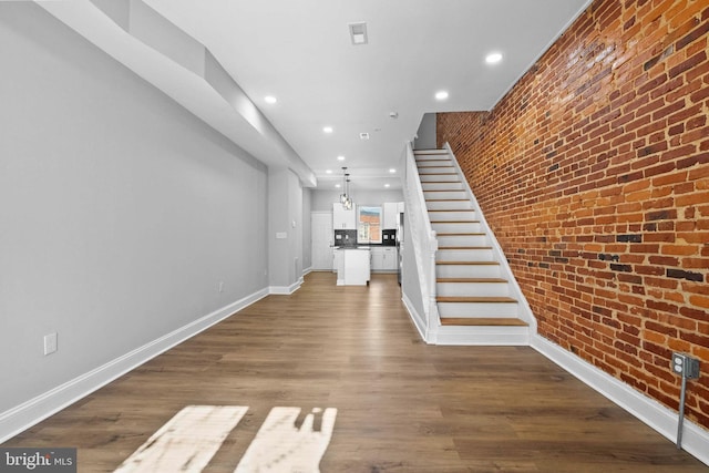 interior space featuring hardwood / wood-style floors and brick wall