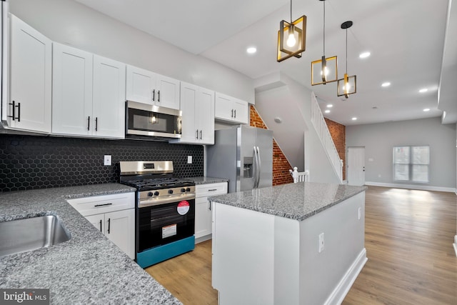 kitchen featuring white cabinets, light hardwood / wood-style floors, hanging light fixtures, and appliances with stainless steel finishes