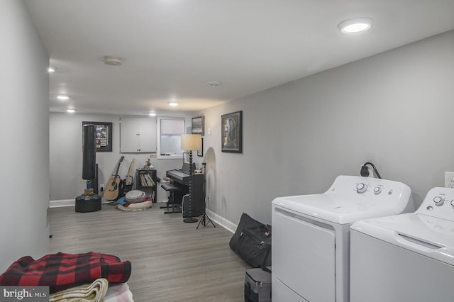 clothes washing area with washing machine and dryer and light hardwood / wood-style flooring