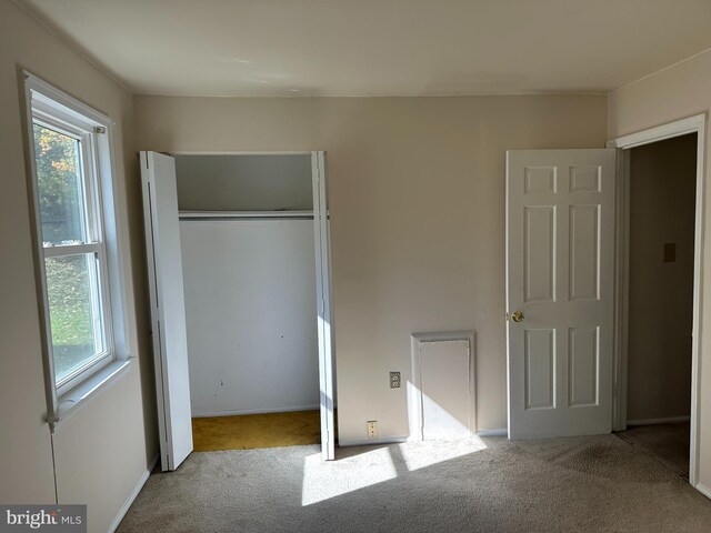 unfurnished bedroom featuring light carpet and a closet