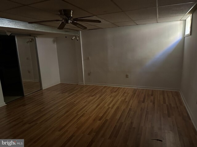 empty room with ceiling fan, a drop ceiling, and wood-type flooring