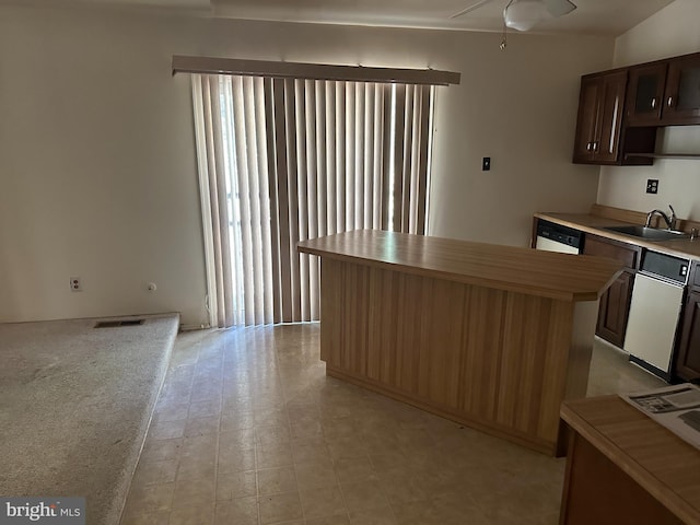 kitchen featuring dishwasher, sink, a kitchen island, and vaulted ceiling