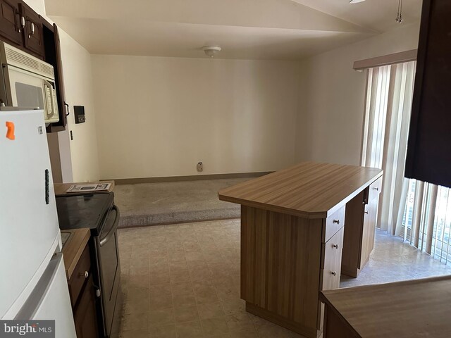 kitchen featuring white appliances, a kitchen island, and dark brown cabinetry