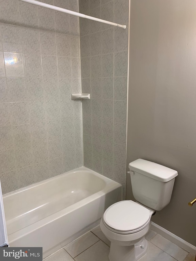 bathroom featuring tile patterned flooring, tiled shower / bath combo, and toilet